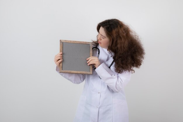 young model girl in white uniform holding a frame.