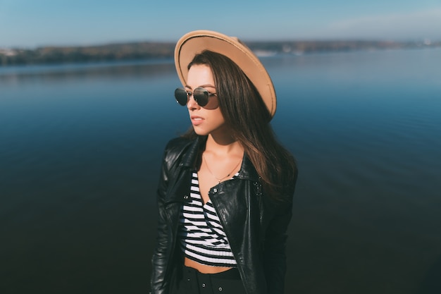 Молодая модель девушка женщина позирует в осенний день на берегу озера, одетая в повседневную одежду