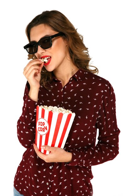 Young model in glasses eating popcorn and posing 