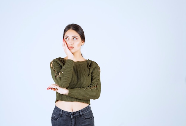 A young model in green blouse posing over white wall