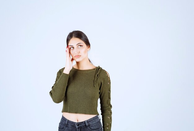 A young model in green blouse thinking about something over white wall