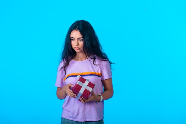 Young model holding a red gift box but looks depressed