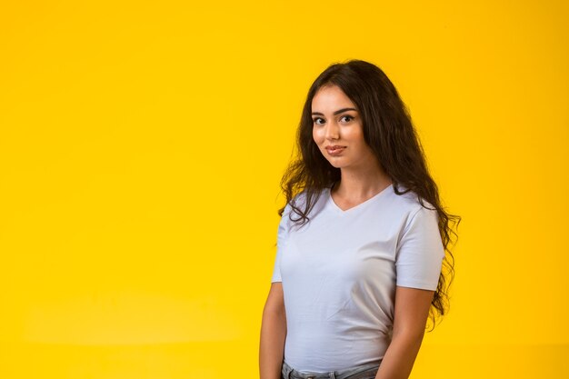 Young model posing at yellow wall and smiling.