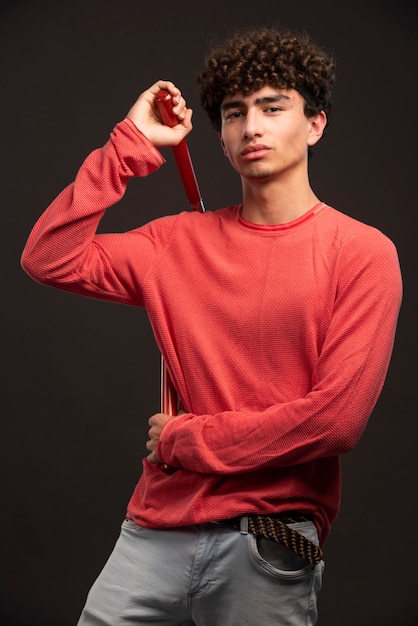 空手ヌンチャクを保持している赤いシャツの若いモデル。