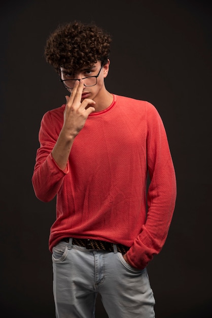 Young model in red shirt wearing eyeglasses with fingers. 