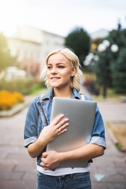 Young model stand on the street with laptop in the city autumn morning