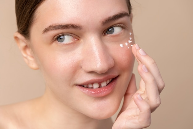 Young model using eye cream high angle