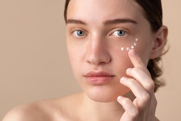 Young model using eye cream side view