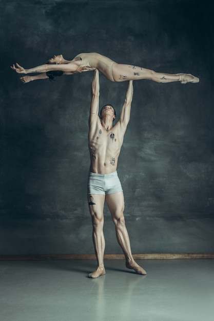 young modern ballet dancers posing on gray