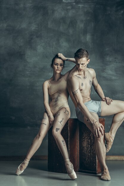 young modern ballet dancers posing on gray