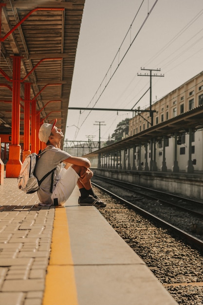 Foto gratuita giovane ragazzo moderno che aspetta dalla piattaforma per il treno per arrivare