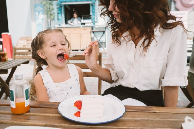 Молодая мама ест торт с улыбающимся ребенком на улице
