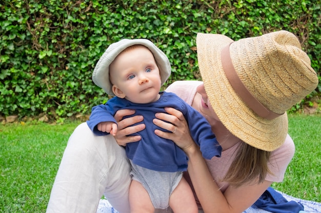Young mom in hat holding daughter, looking at her
