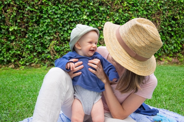 Free photo young mom with face covered by hat holding daughter