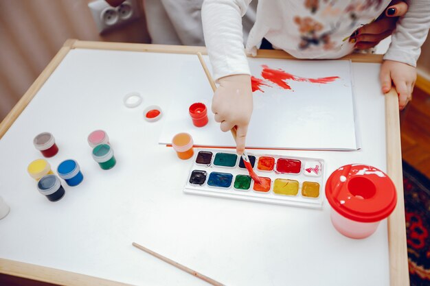 A young mother, along with her little daughter paints on paper