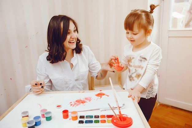 A young mother, along with her little daughter paints on paper