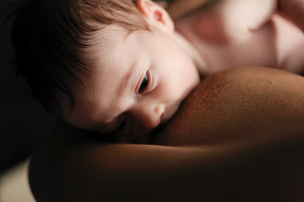 Young mother breastfeeding newborn baby at home