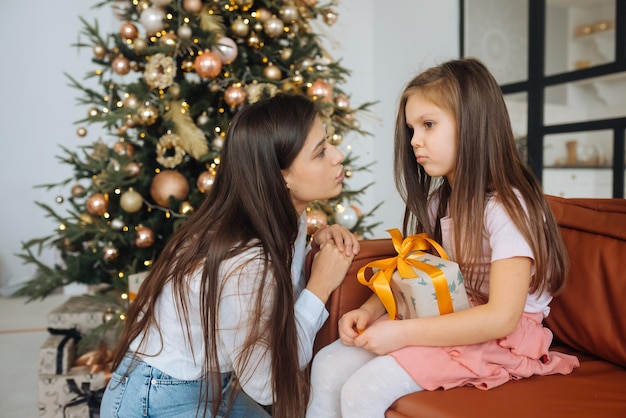 Young mother calming down her sad infant daughter sitting