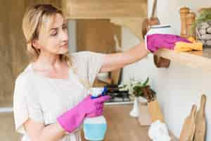 Free photo young mother cleaning the shelves in the house