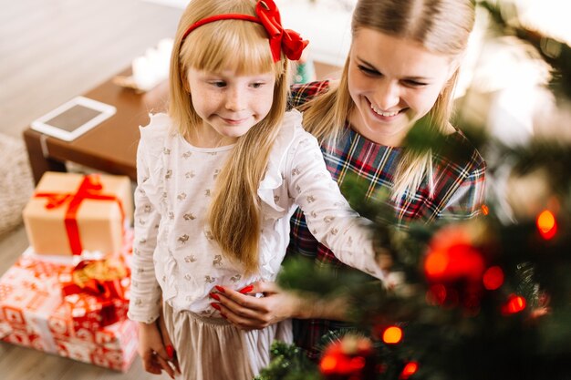 Young mother and daughter decorating christmas tree