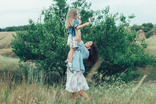 The young mother and daughter on green grass space