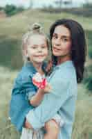 Free photo the young mother and daughter on green grass space