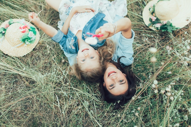 The young mother and daughter with candies on green grass