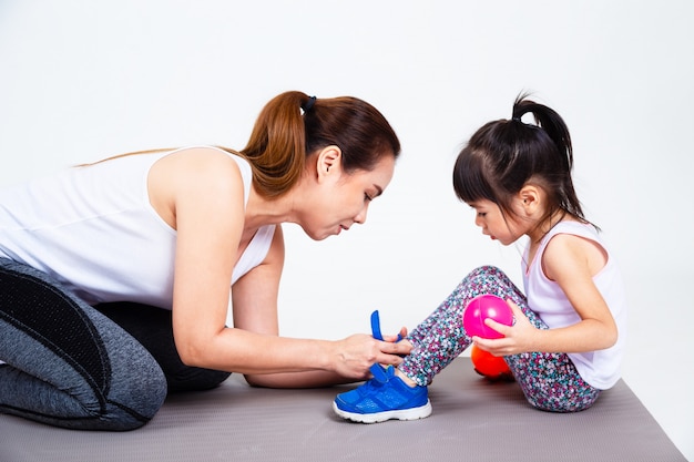 Young mother help cute daughter wearing shoes