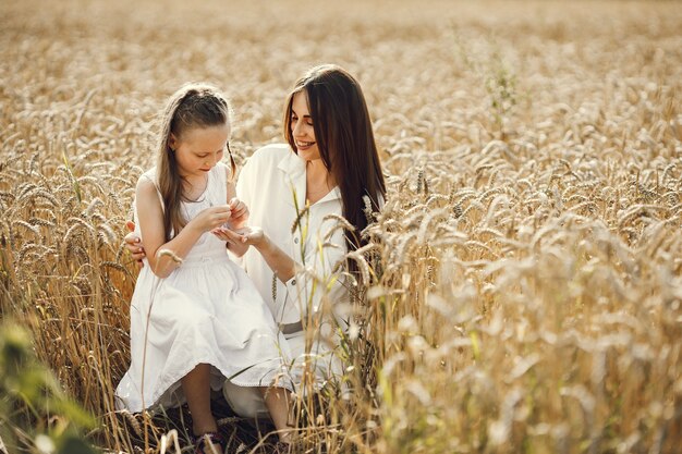 화창한 날 밀밭에서 하얀 드레스를 입은 젊은 엄마와 딸.