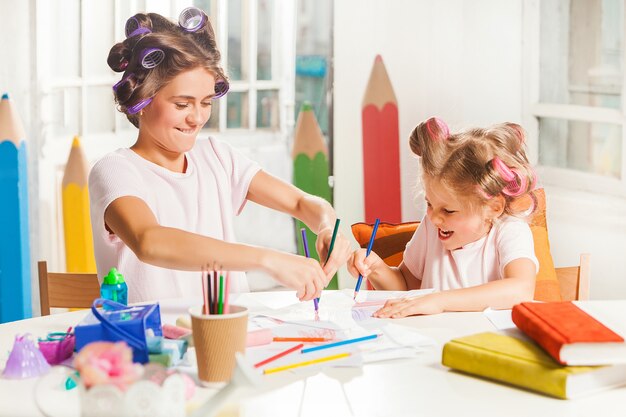 젊은 어머니와 그녀의 작은 딸 집에서 연필로 그리기