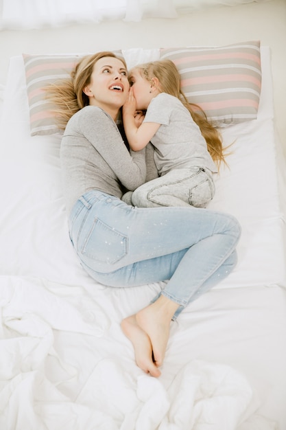 Young mother and her little daughter at home at sunny morning. Soft pastel colors. Happy family time on weekend. Mother's Day concept. Family, love, lifestyle, motherhood and tender moments concepts.