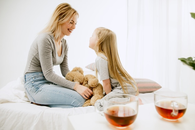 Foto gratuita giovane madre e la sua piccola figlia a casa al mattino pieno di sole. colori pastello tenui. tempo in famiglia felice nel fine settimana.