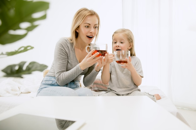 晴れた朝、家にいる若い母親と幼い娘。やわらかなパステルカラー。週末の幸せな家族の時間。