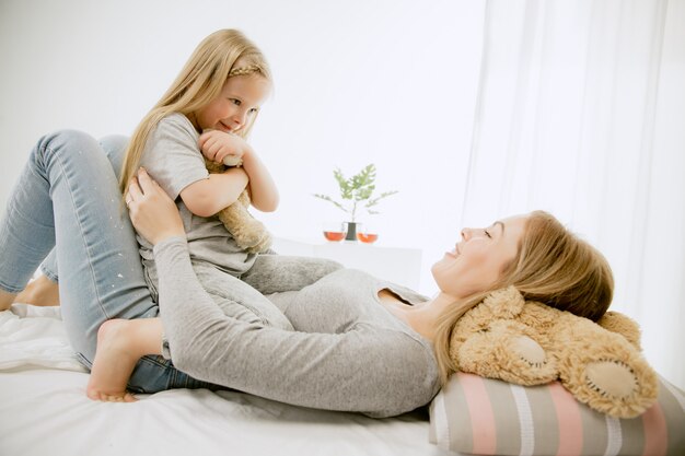 Young mother and her little daughter at home at sunny morning.