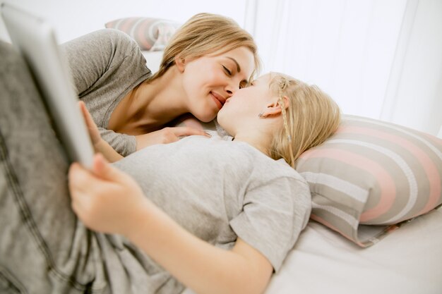 Young mother and her little daughter at home at sunny morning.