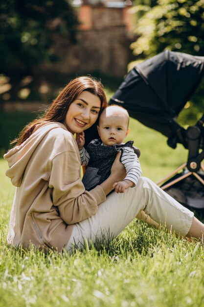 잔디에 앉아 그녀의 아기와 함께 공원에서 젊은 어머니
