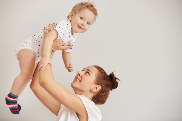 Foto gratuita giovane madre che gioca con il suo piccolo bambino sul letto