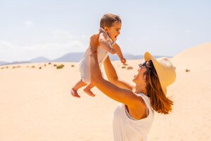 コラレホ自然公園の砂丘で休暇中に息子と遊ぶ若い母親