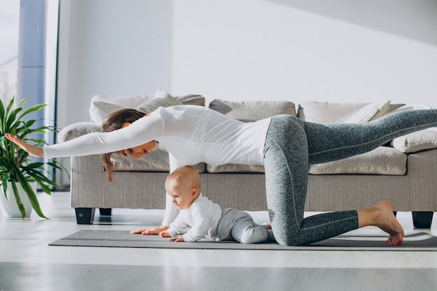 La giovane madre pratica lo yoga con il figlio piccolo sul tappetino