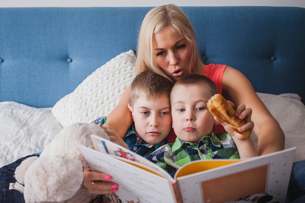 Free photo young mother reading a book to her children