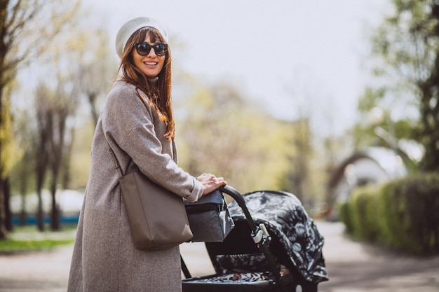 Young mother sitting with baby carriage in park