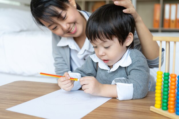 Молодая мама учит сына писать на бумаге с любовью
