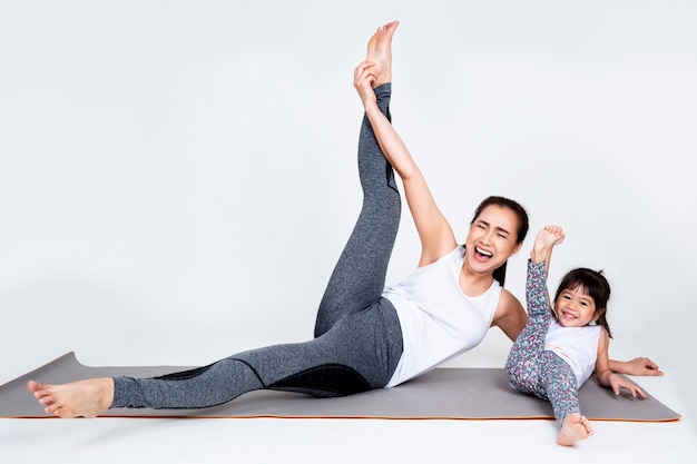 Young mother training lovely daughter with gymnastic