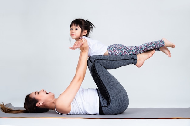 Young mother training lovely daughter with gymnastic