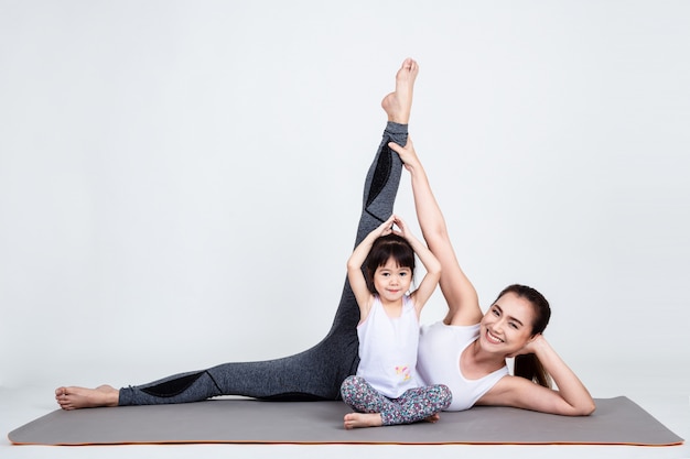 Young mother training lovely daughter with yoga