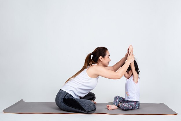 Young mother training lovely daughter with yoga