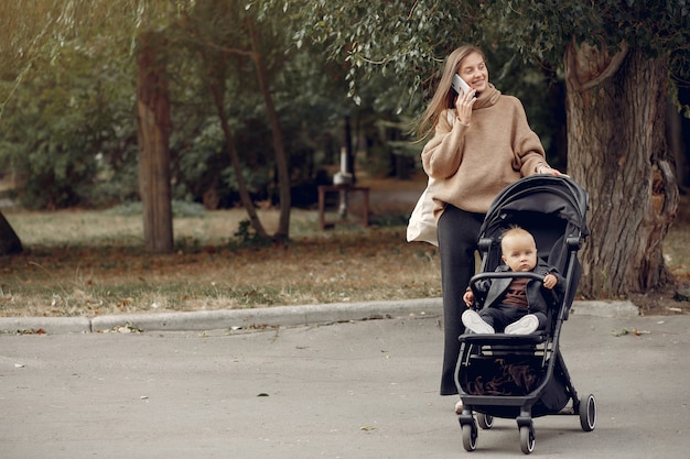 Young mother walking in a autumn park with carriage