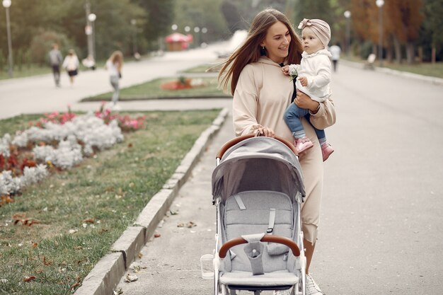 Young mother walking in a autumn park with carriage