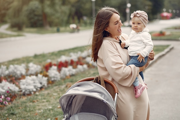 Young mother walking in a autumn park with carriage