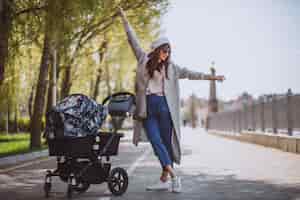 無料写真 ベビーカーを公園で歩く若い母親